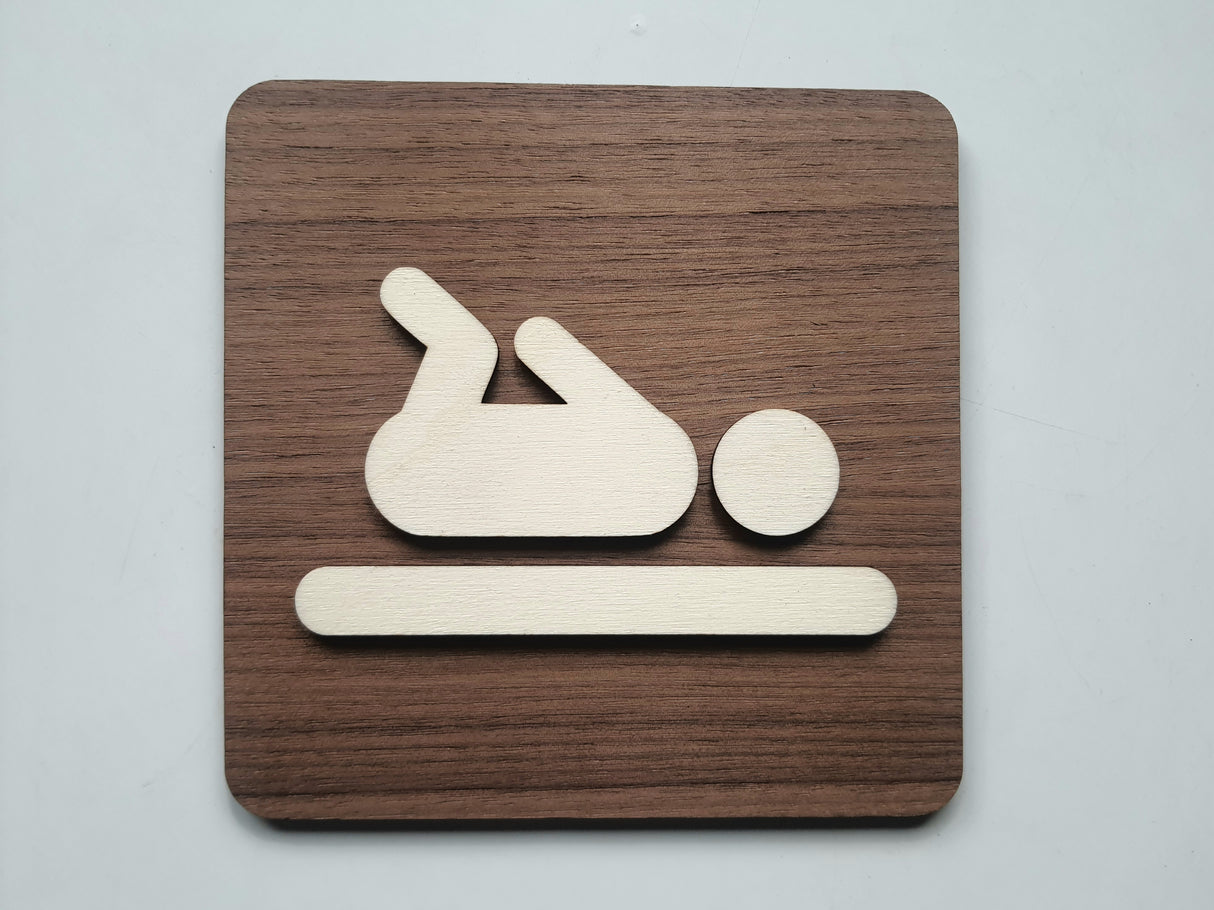 Pusleplads skilt i træ med baby piktogram på valnød baggrund – frontvisning