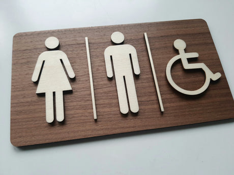 Rektangulært toilet skilt i træ vist fra vinklet side med piktogrammer