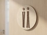 Detalje af toiletskilt i træ med lys birkebaggrund og elegante piktogrammer